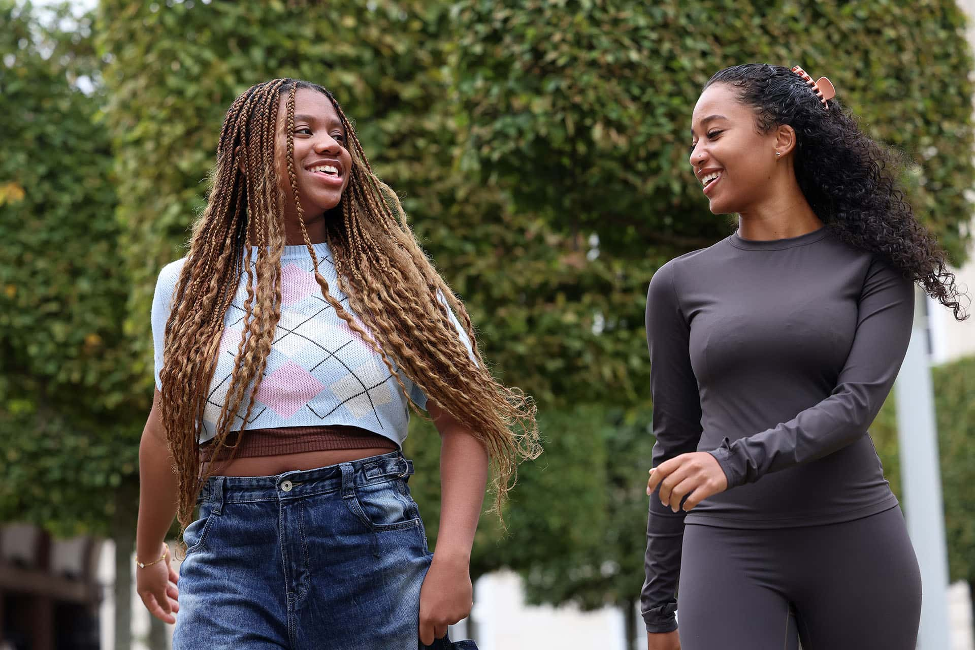 two female students walking on campus with trees in the background