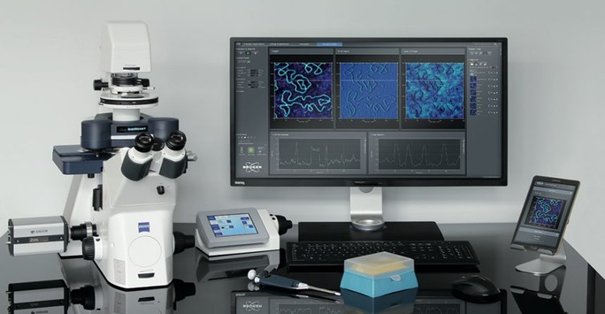 A desk featuring a computer, microscope, and various electronic devices arranged neatly for scientific work.