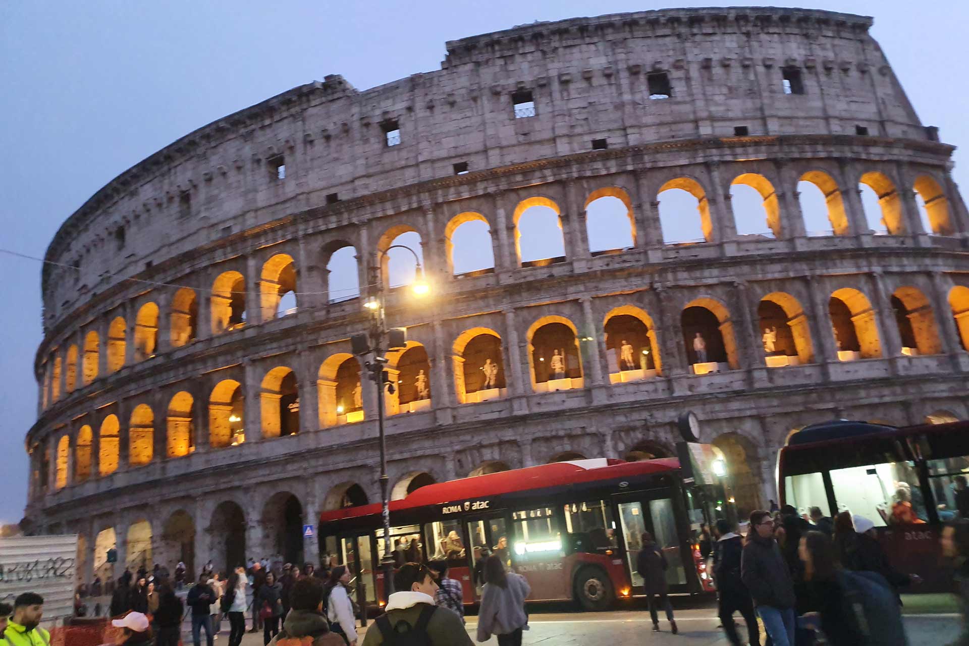 A Colosseum at dusk, with lights inside from within