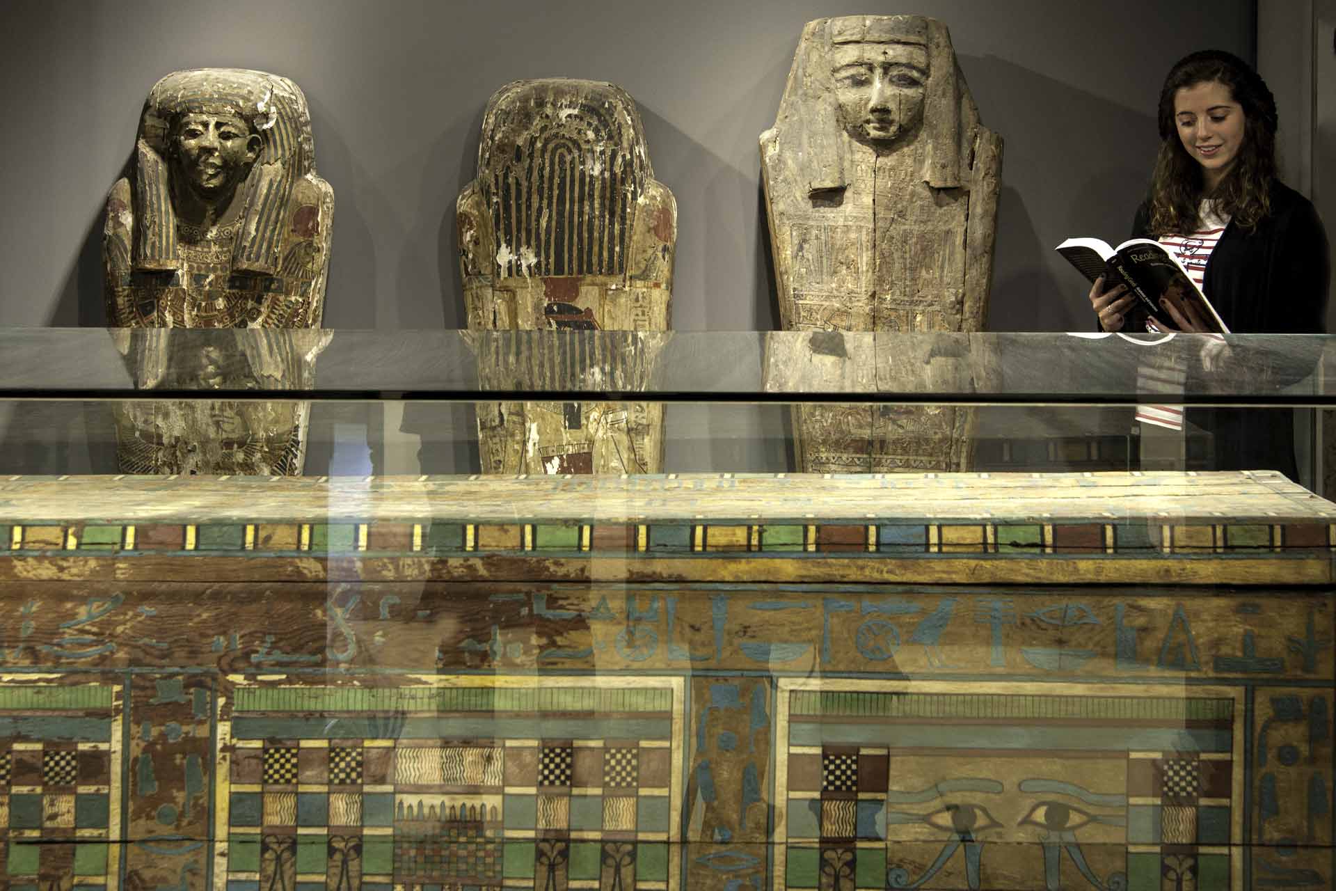 Egyptian tomb and mummies inside museum with student reading textbook