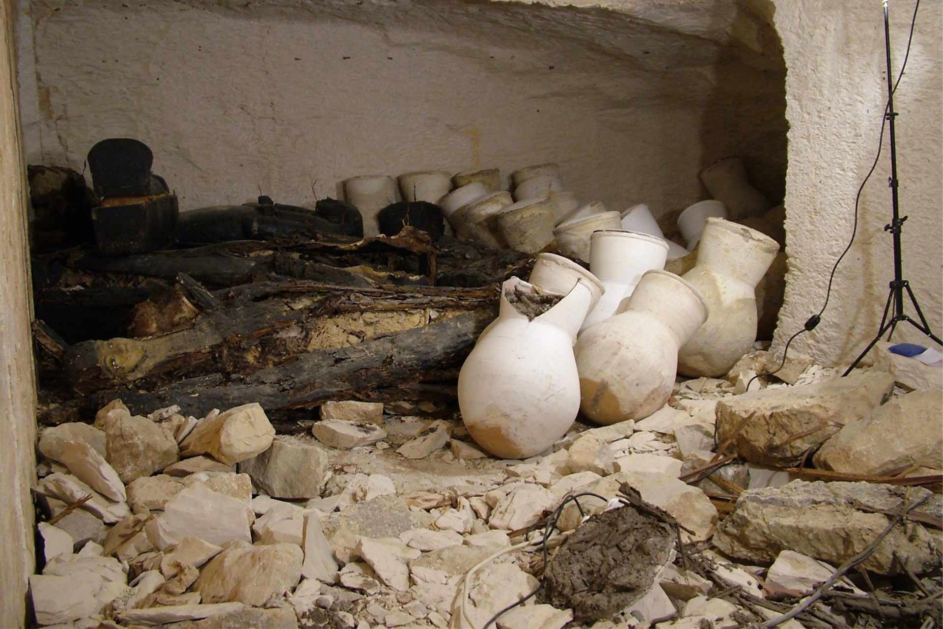 Inside of a tomb filled with rubble and ornamental objects made of stone that look like urns