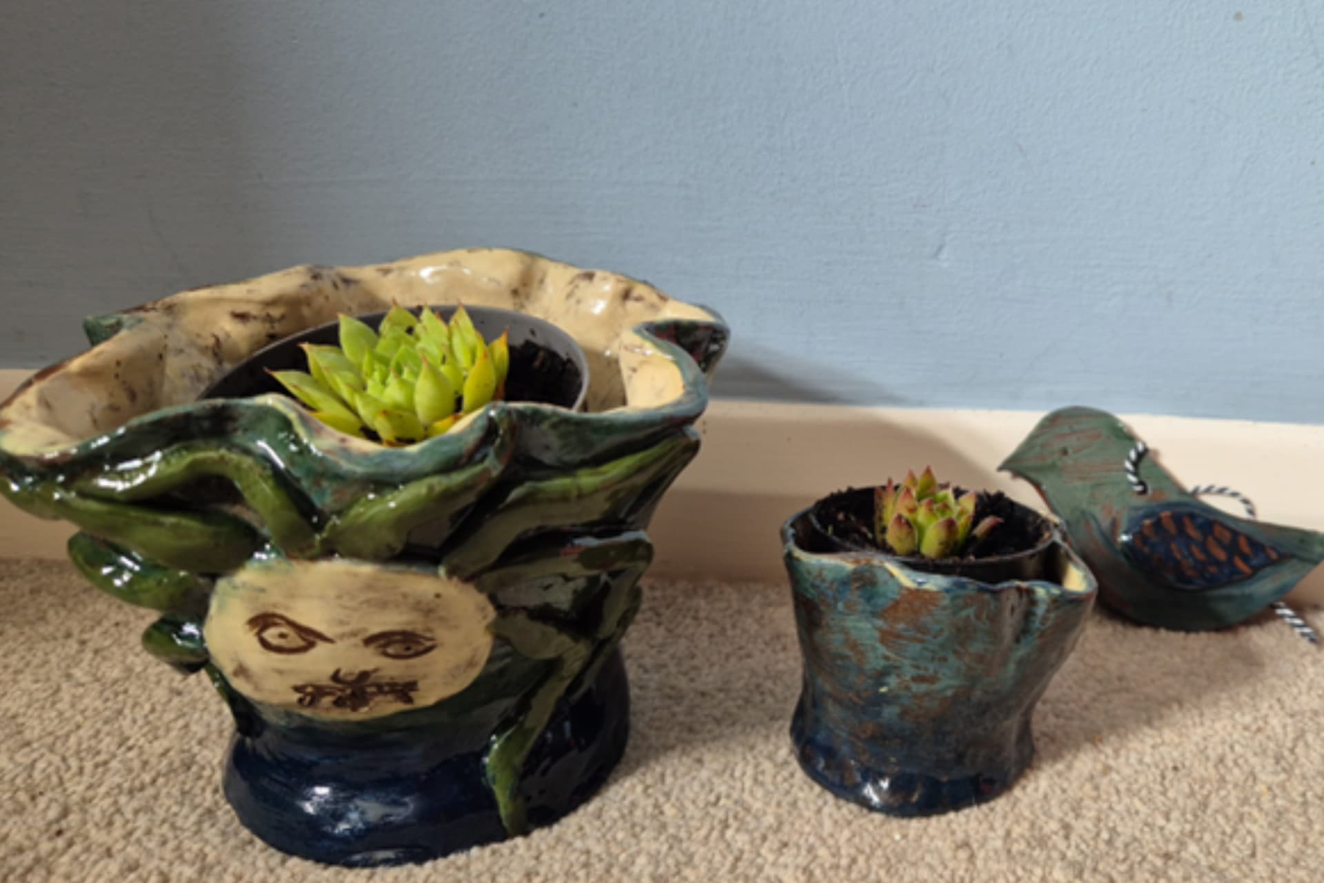 A plant pot and other pottery. A plant resides inside the Gorgon plant pot.