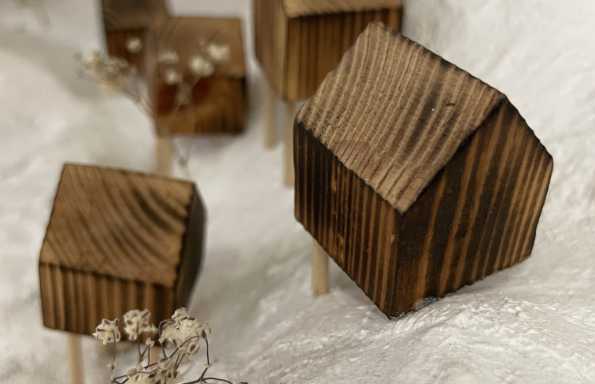 SMall wooden models of houses with pitched roofs set in a contoured landscape with model trees.