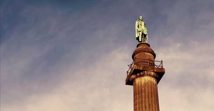 Misty sky with a bronze statue of Wellington on top of a stone column in the foreground.