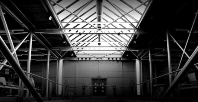 Steel roof over a wide atrium with metal walls.