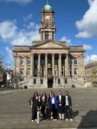 A group of women and men standing outside a victorian town hall.