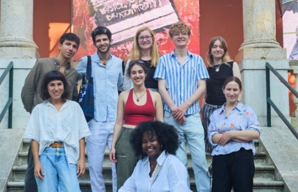 A group of young people standing on a stone staircase, two columns are behind them at the top.