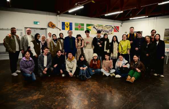 Two lines of students looking at the camera, photographed in a warehouse.