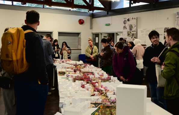 A group of people standing around an architectural model.