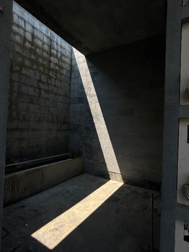 A shaft of light falling on a concrete wall and floor.