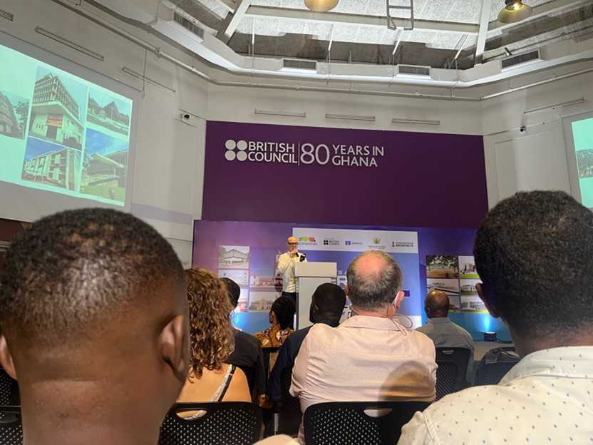 A grouple of people sitting in a lecture room listening to a man give a lecture.