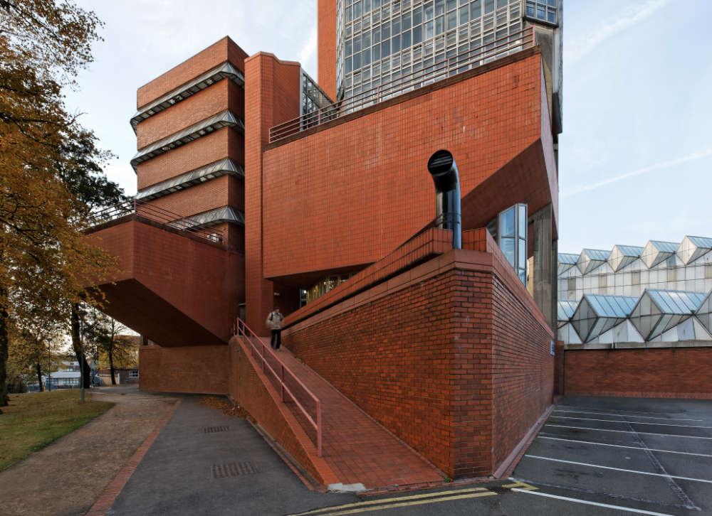 Wide angle corner shot of a modern brick building with glass walls and roofing.