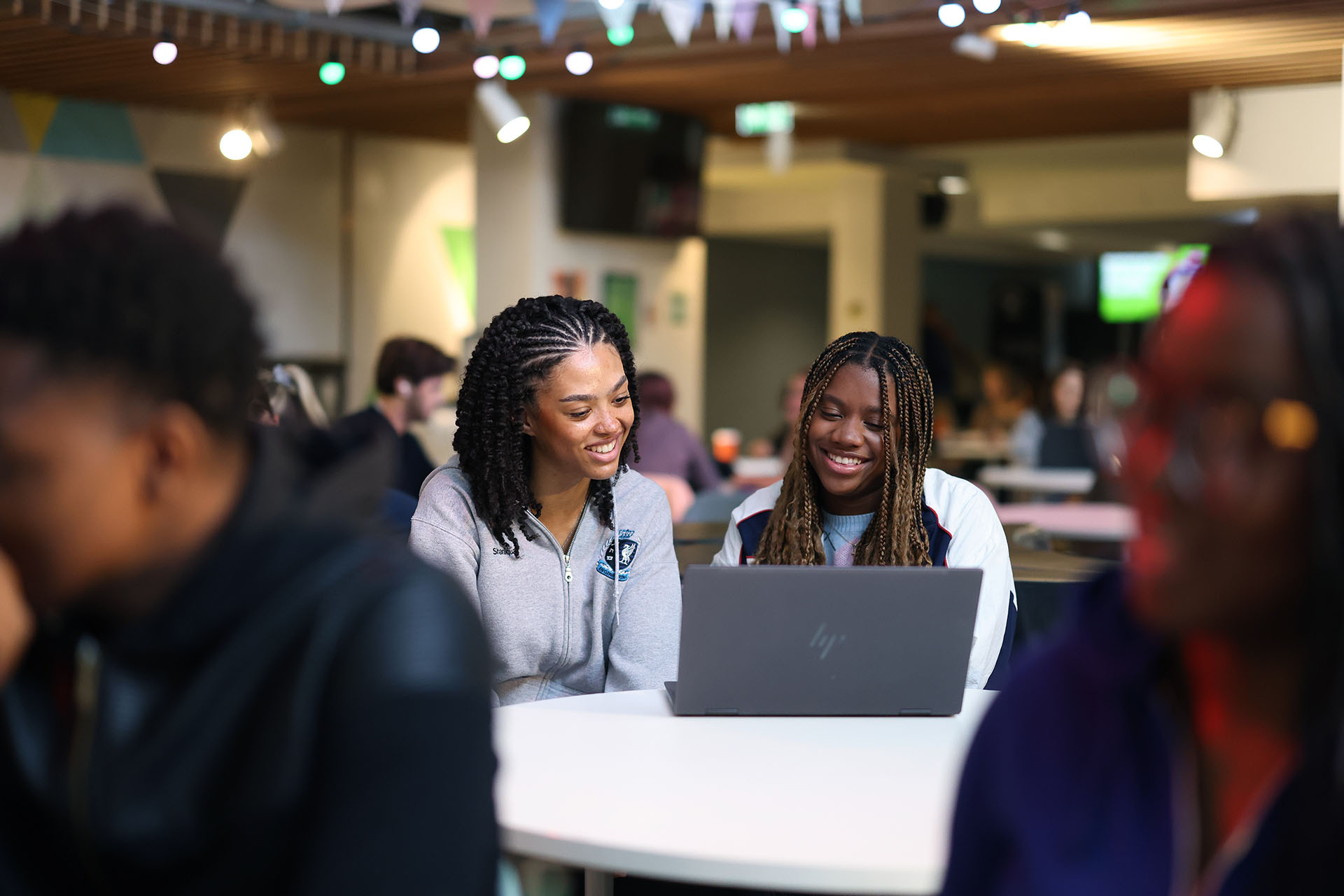 Two students sitting at a table in the Guild of Students with a laptop