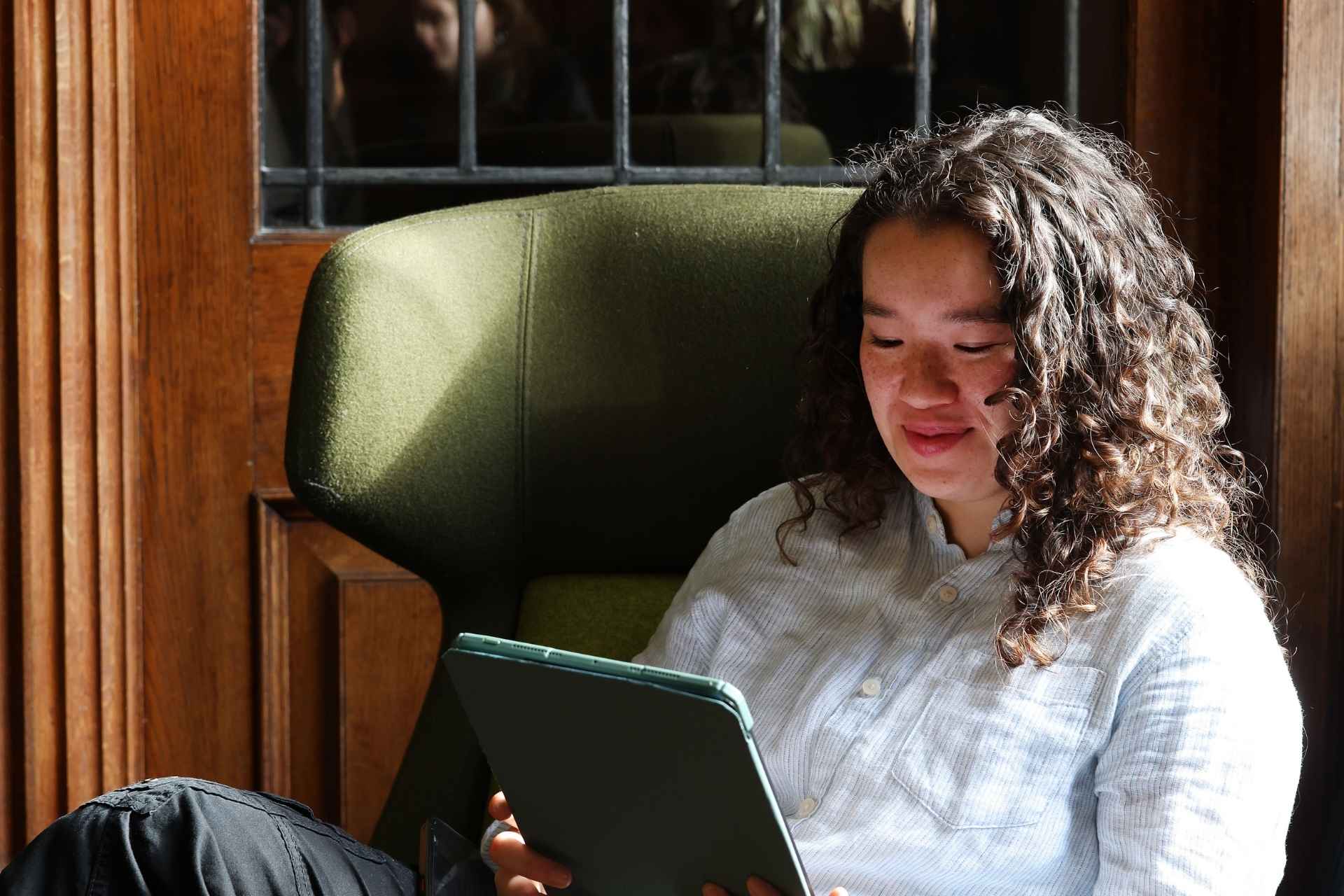graduate sitting on green sofa replying to mentees n handshake