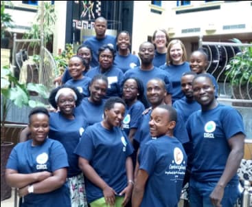 A group of researchers in Nigeria are all wearing the same tshirt, standing in a group smiling at the camera