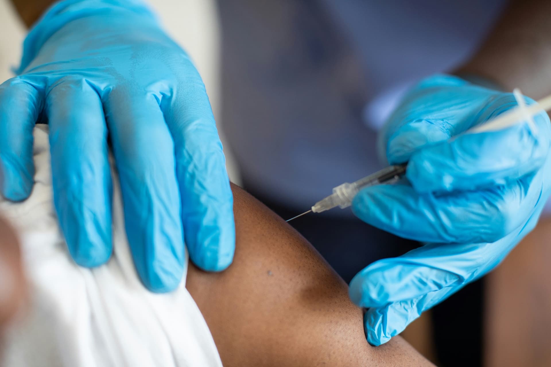 a doctor is about to inject medicine into a patient's upper arm
