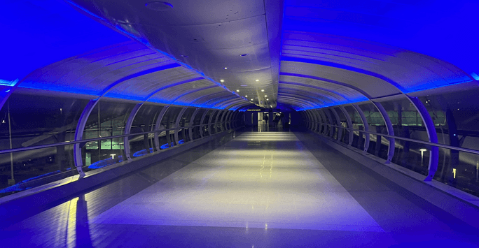 Empty enclosed pedestrian bridge, lit up in blue and white light