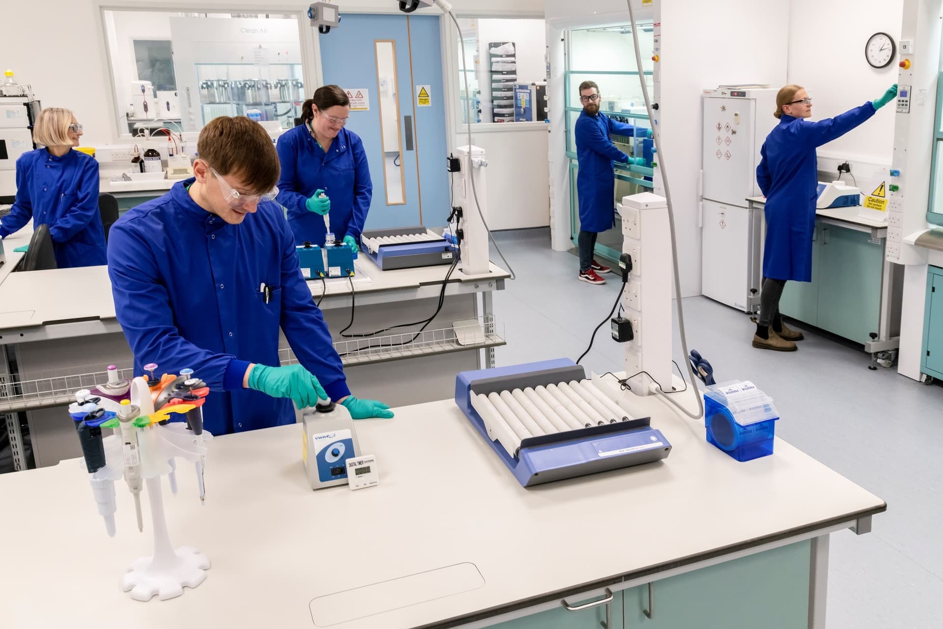 A group of 5 people in blue uniforms in chemistry lab