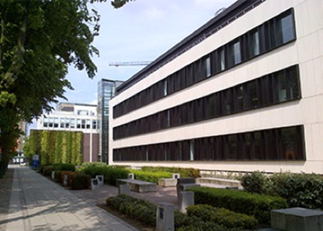 A large white building surrounded by green trees under a clear blue sky.