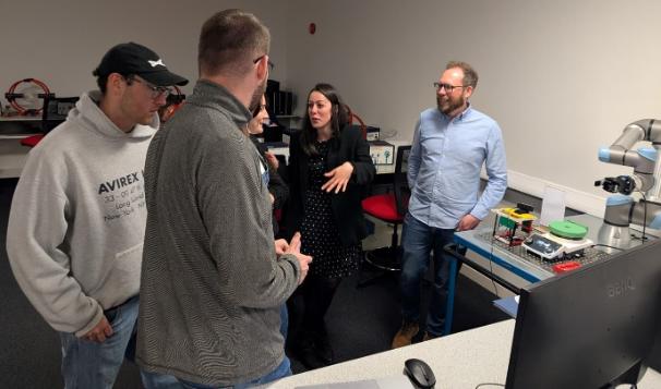 A diverse group of people gathered around a computer, engaged in discussion and collaboration.