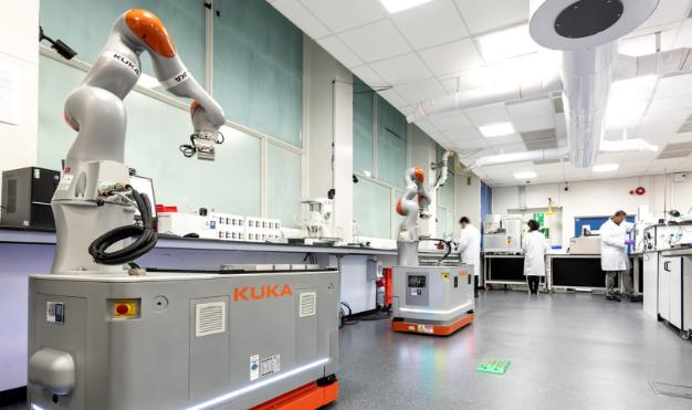 A robot is positioned in a lab, with a man standing next to it, showcasing innovation in a scientific environment.