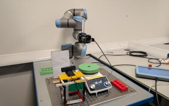 A robot sits on a table next to a computer, showcasing a blend of technology and innovation in a workspace setting.