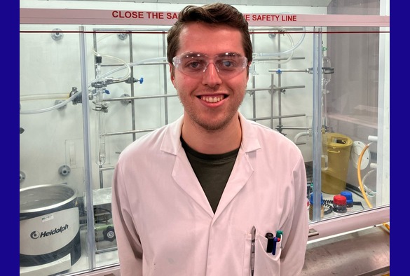 Ross Adams in a lab wearing white lab coat and safety lab goggles