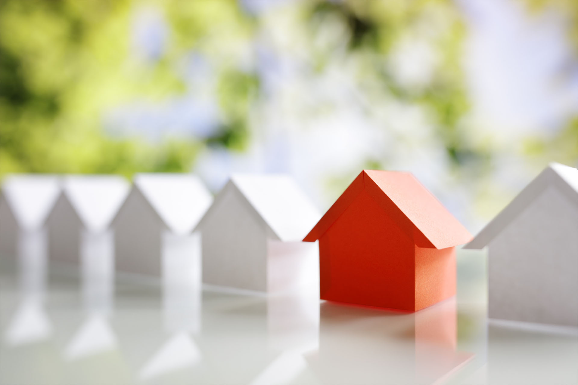 Models of white houses with one red model house