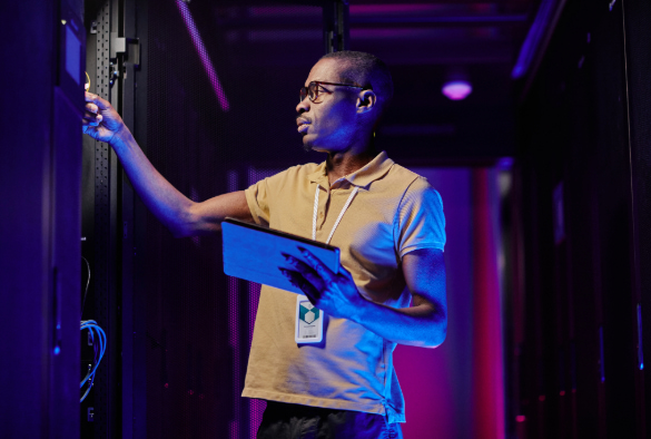 IT staff member holding tablet and looking at computer system