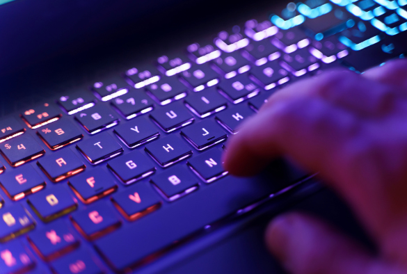 Close up of keyboard with neon lights and hand placed over it