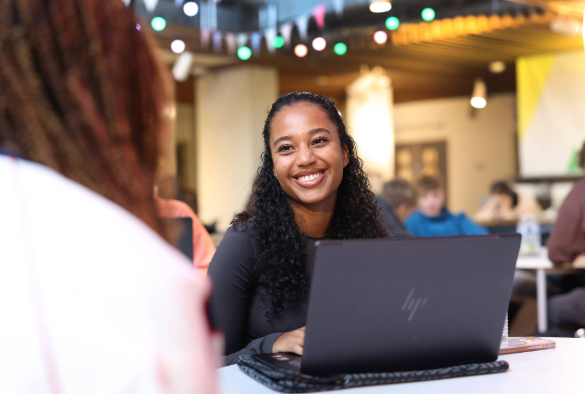 Student smiling with another student while studying in the guild of students