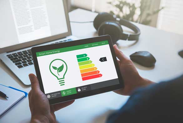 Over shoulder view of user looking at energy rating on a tablet, laptop open on a desk in the background