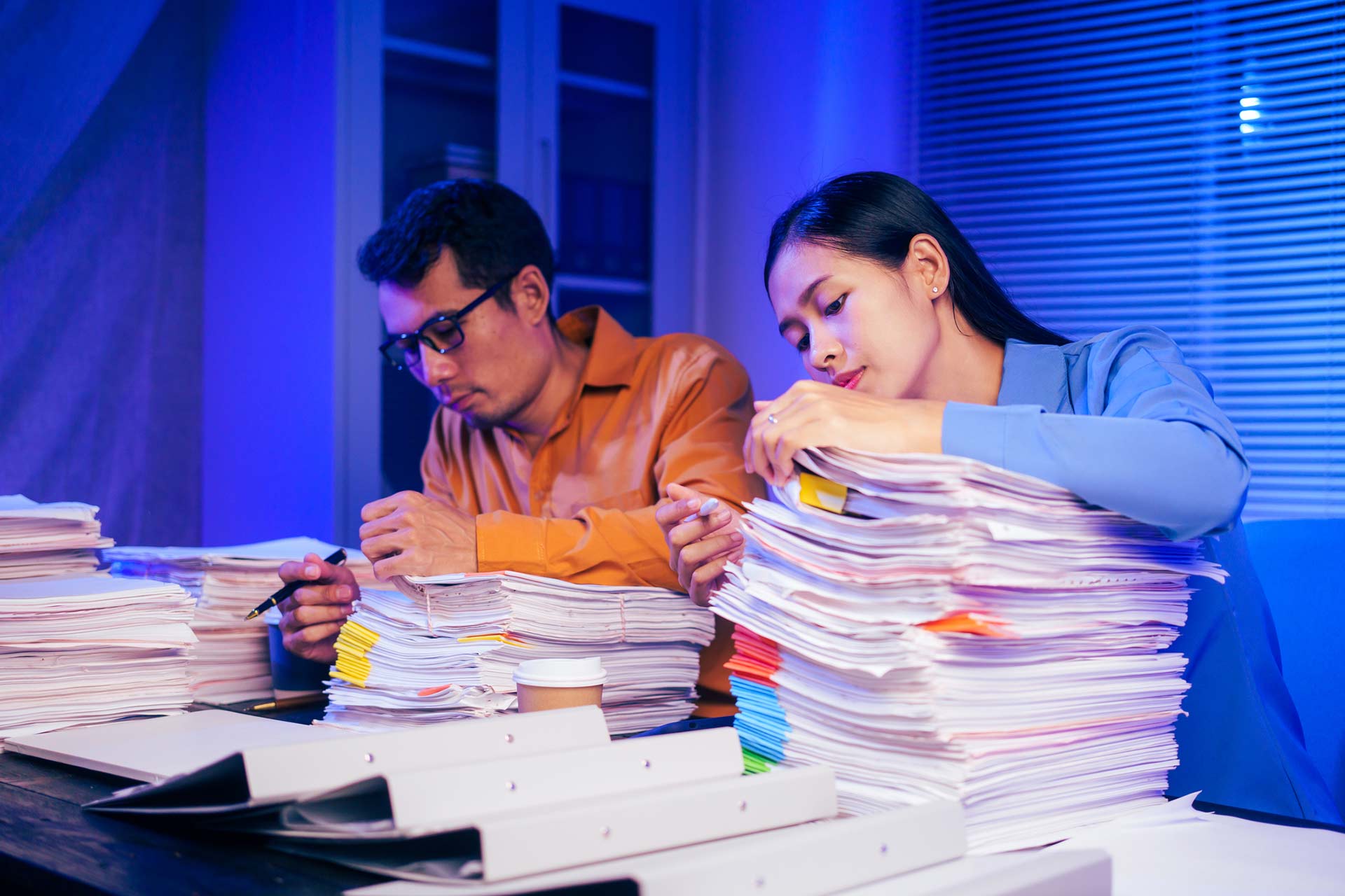 colleagues sitting next to one another searching through paperwork