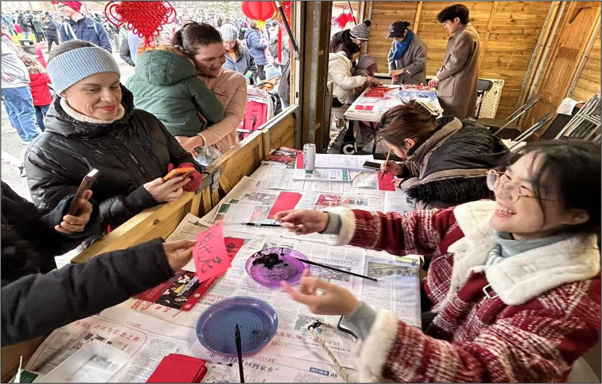 Members of the public doing Chinese Calligraphy with LCI staff at Chinese New Year celebrations in Chinatown