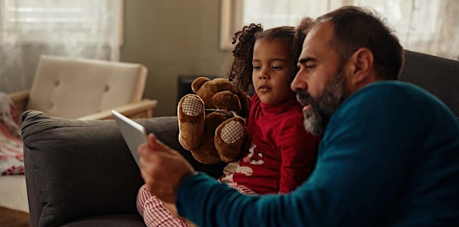 Man and young child looking at a tablet screen together