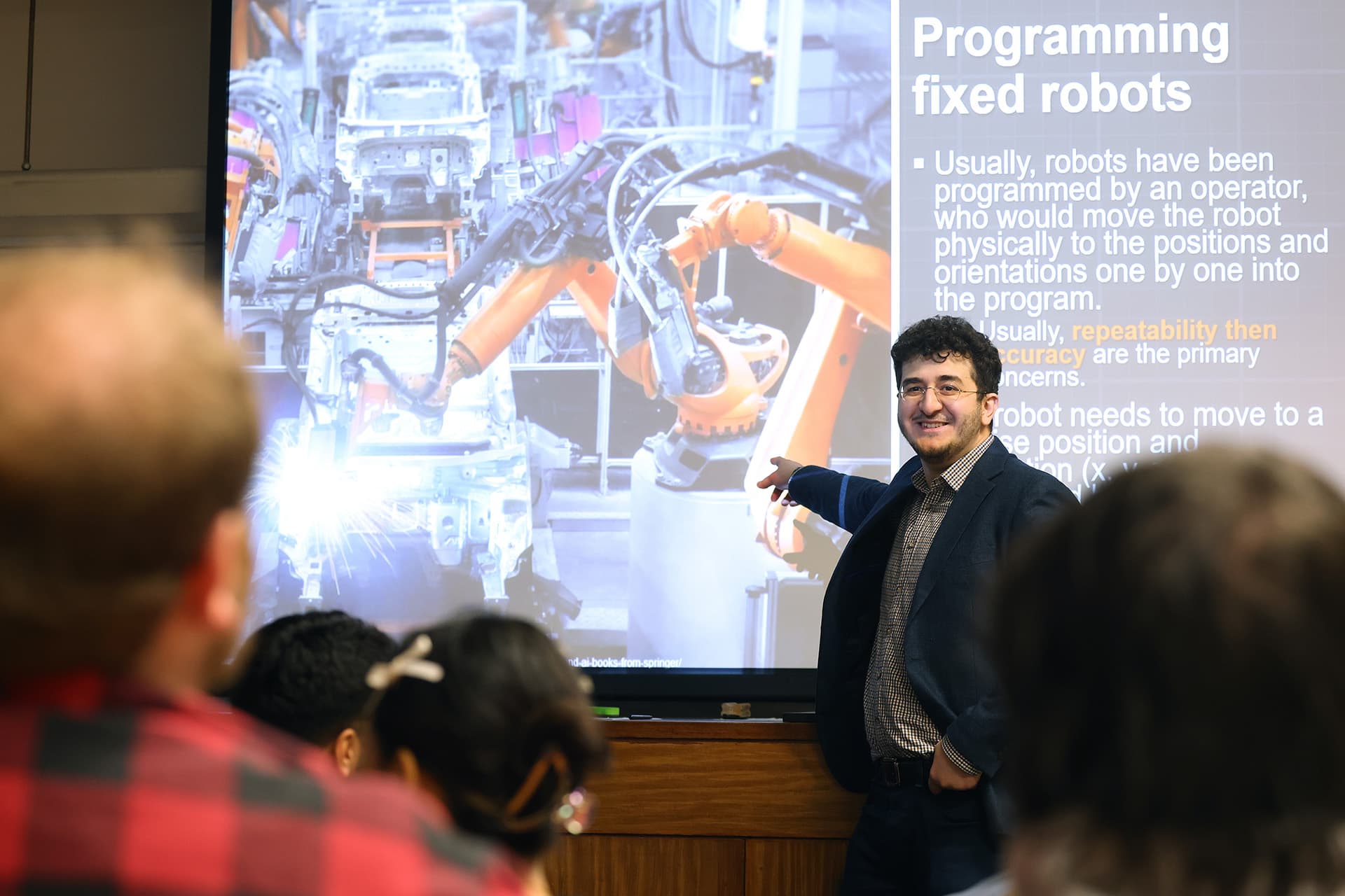 Lecturer pointing at a presentation in front of students