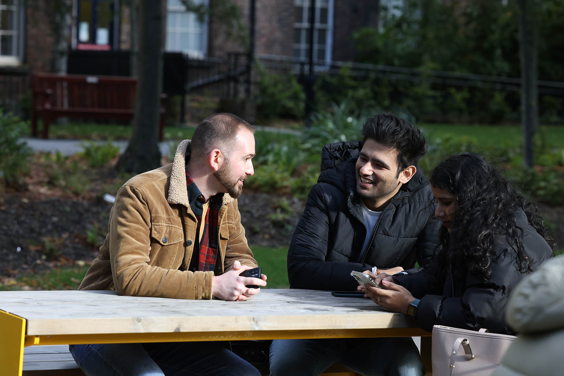 Postgraduate students sitting chatting around a table