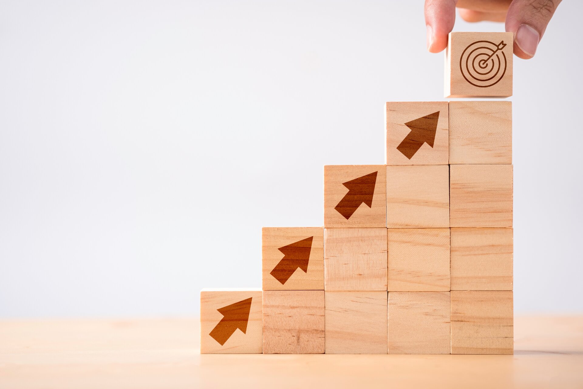 A stack of wooden blocks in a stair pattern pointing towards a target at the top of the stack.