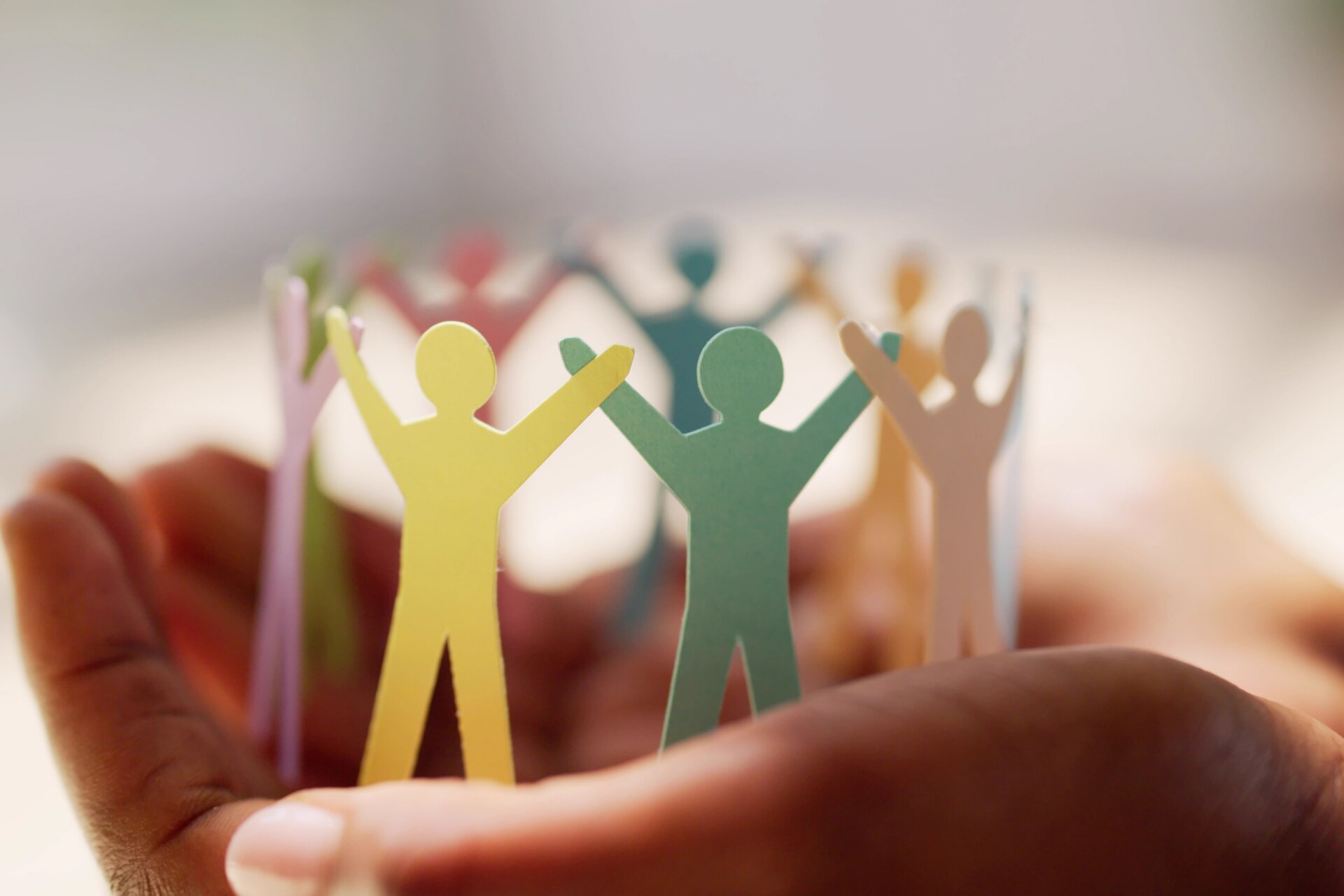 A hand holding a ring of paper cut outs of people