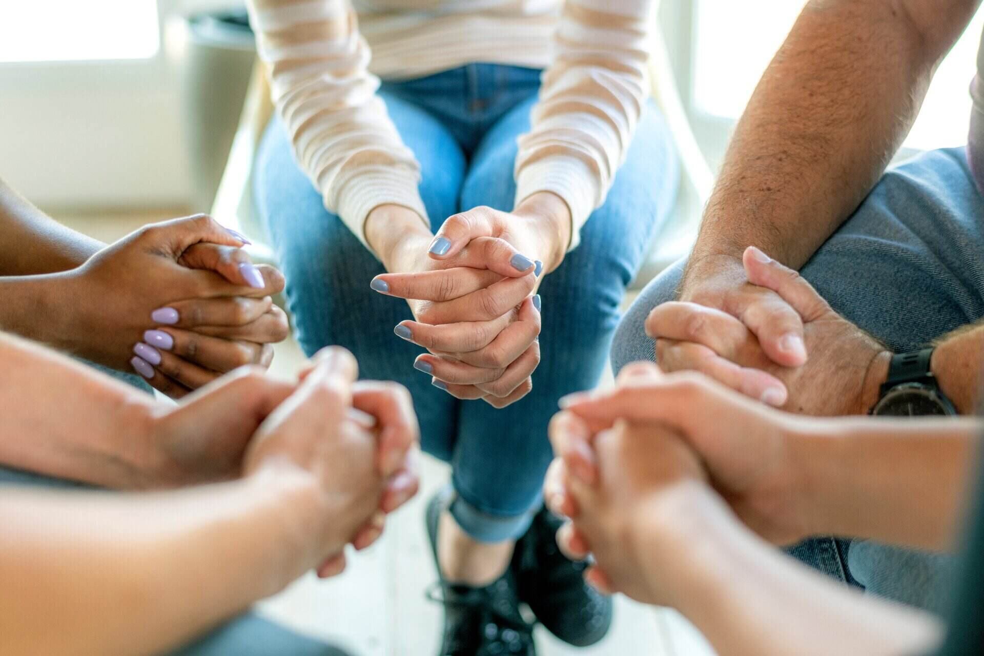 A group of people with hands clasped sitting in a circle