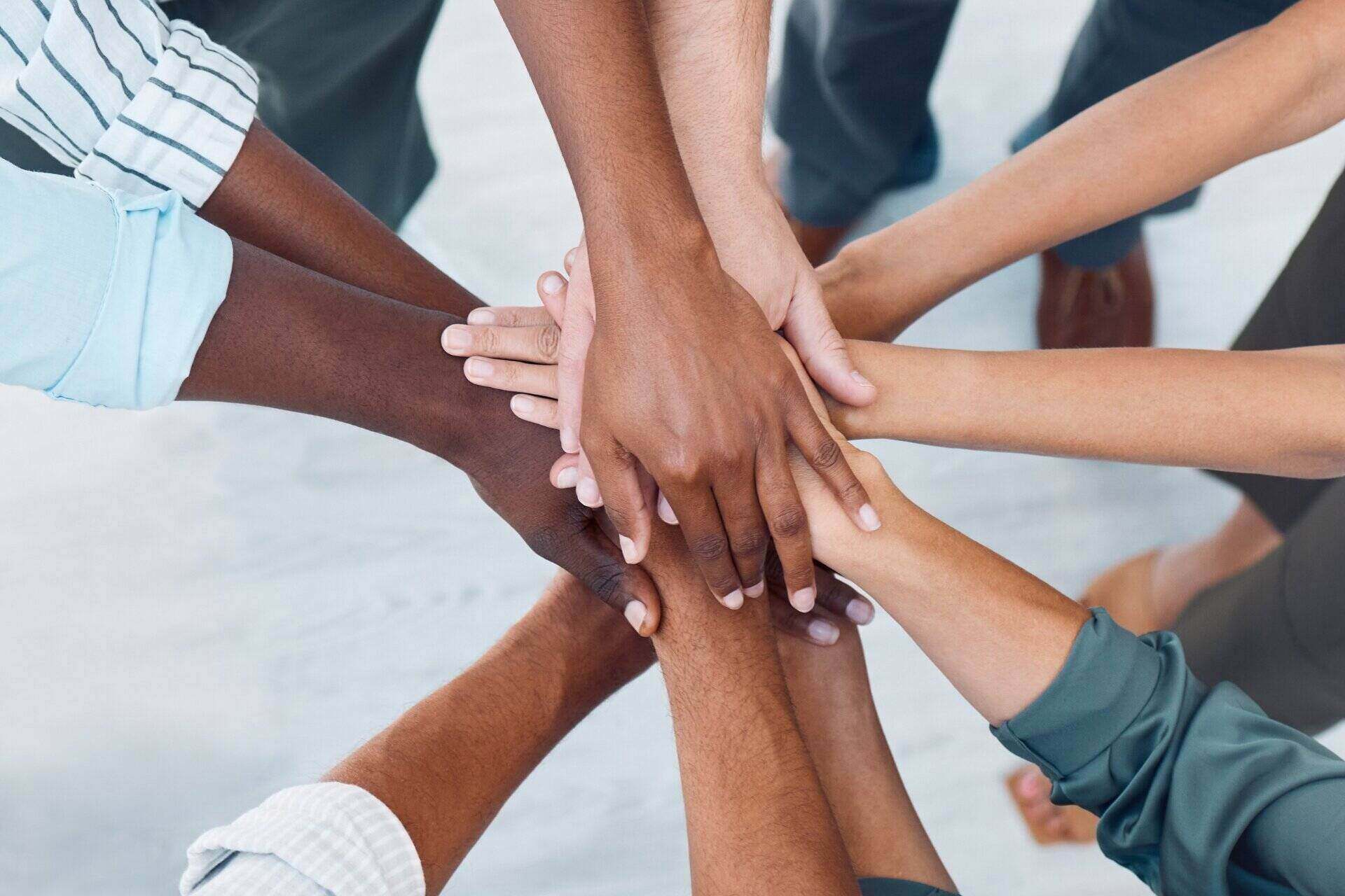 A circle of people putting their hands together in the middle