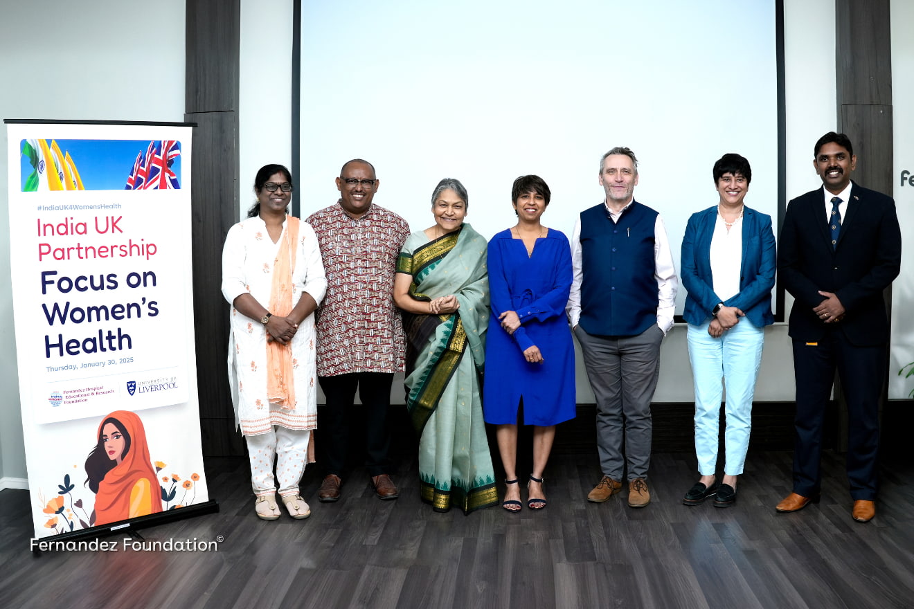 7 event attendees included Prof Shakila Thangaratinam stood in a line smiling next to a promo pop up banner