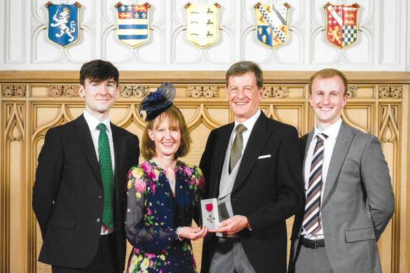 Professor Callum Youngson holds up his MBE alongside his family