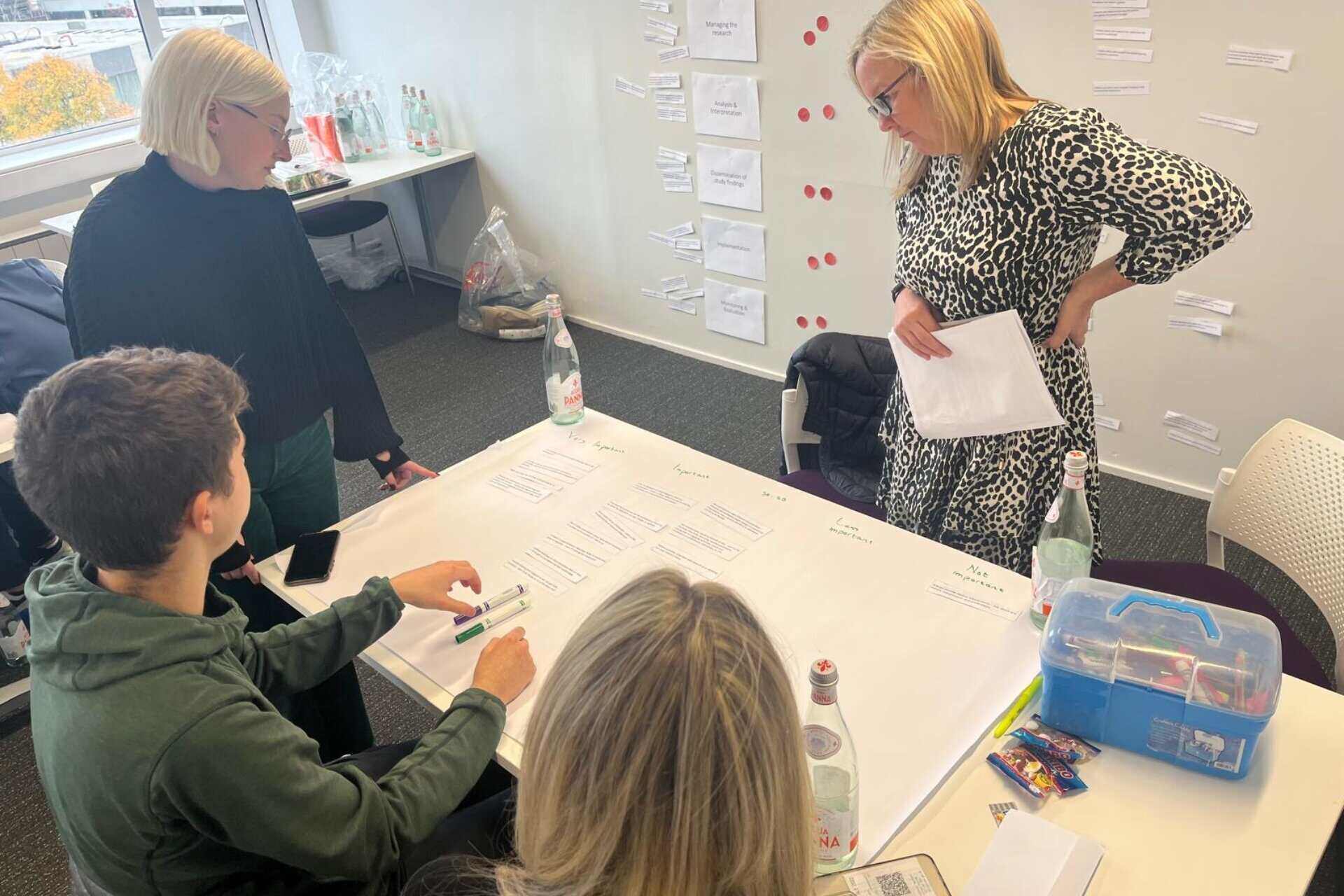 Three women and a young adult male around a desk performing a PPI activity.