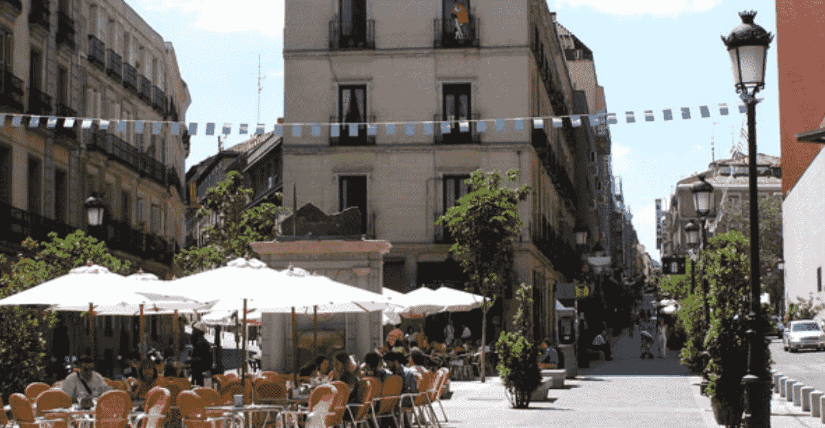 A patio view of Salamanca in Spain, a group of people in the foreground sitting o benches under an umbrella