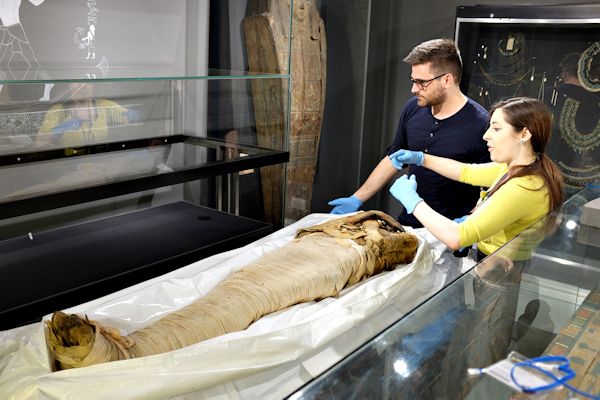 Two curators examining a mummy