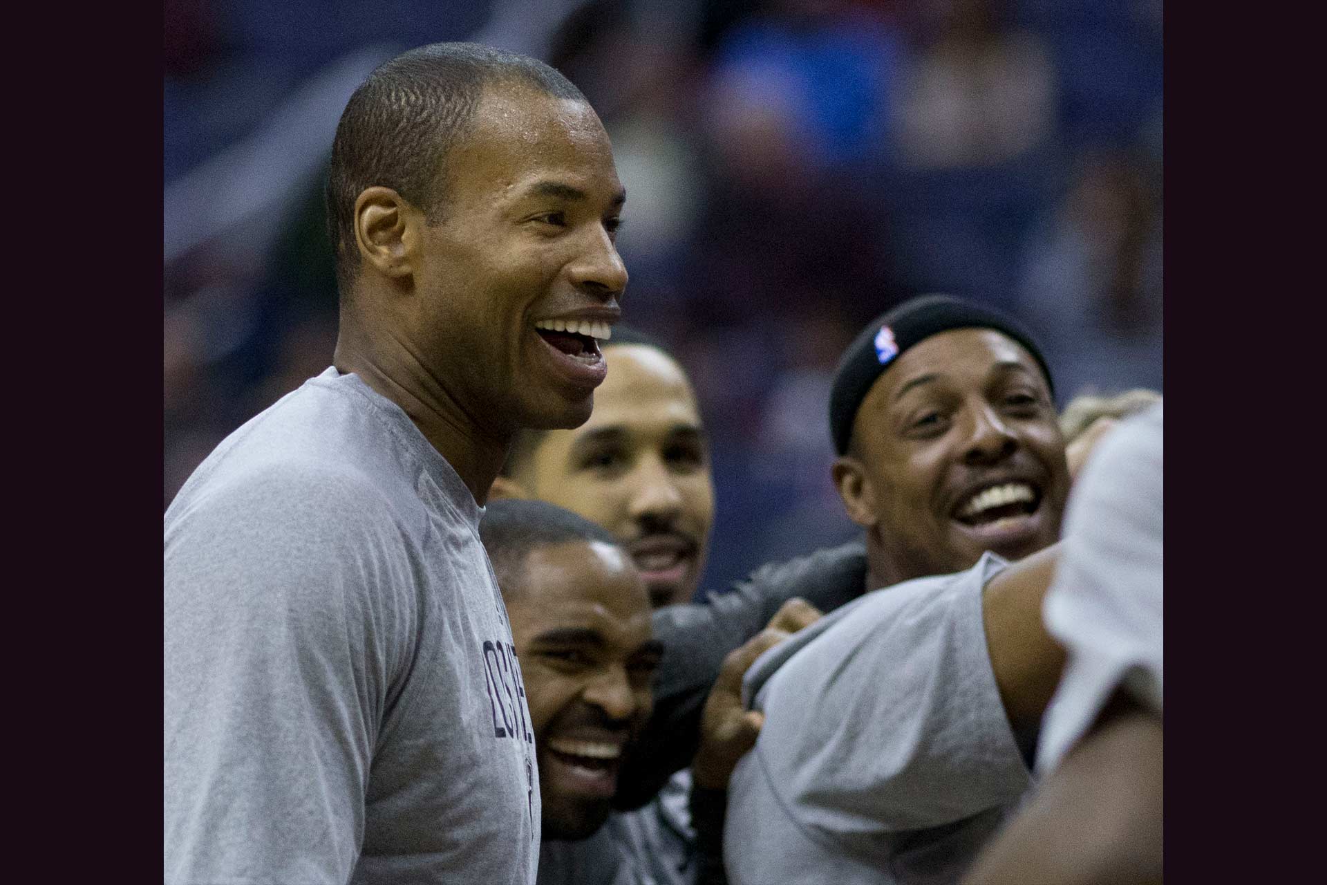 Basketball players wearing grey tshirts smiling, including Jason Collins, a tall man with dark skin