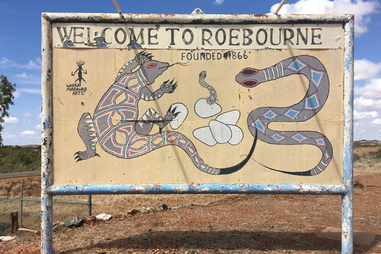 A sign in a desert landscape which says 'Welcome to Roebourne'