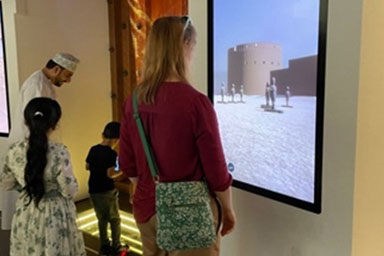 A woman looking at a wall-mounted display board with an image of a building on it