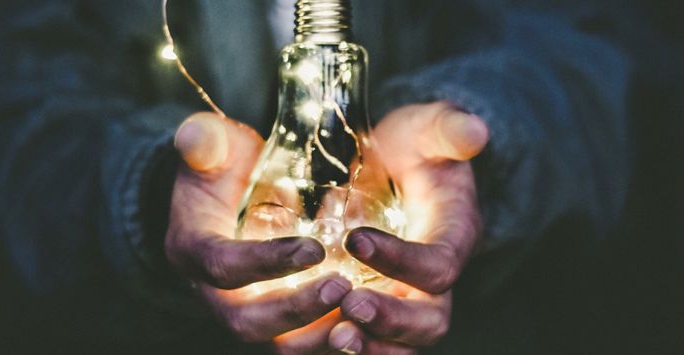 Two hands holding a lightbulb